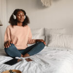 Living with Anxiety: Coping Strategies for Daily Life: Hero Image A woman meditating with closed eyes and headphones on, practicing mindfulness in a peaceful bedroom, symbolizing coping strategies for managing anxiety and promoting mental well-being
