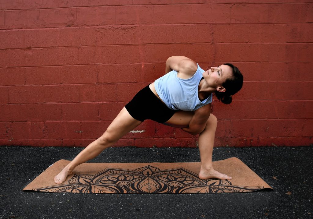 A fit woman does a yoga pose on a mat next to a painted brick wall in this article about How to use HSA/FSA funds on the Lemonaid blog.